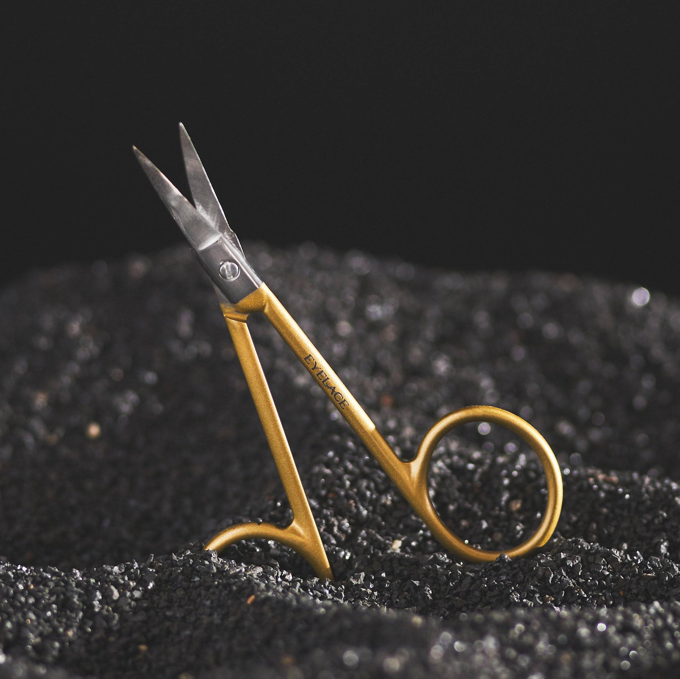 Gold and silver curved blade scissors on black surface